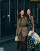 A couple of women standing next to each other on a street.