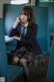 A woman in a school uniform sitting on a train.