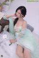 A woman in a green dress sitting on a bed.