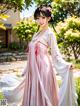 A woman in a pink and white dress standing in a garden.