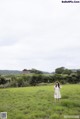 A woman in a white dress standing in a field.